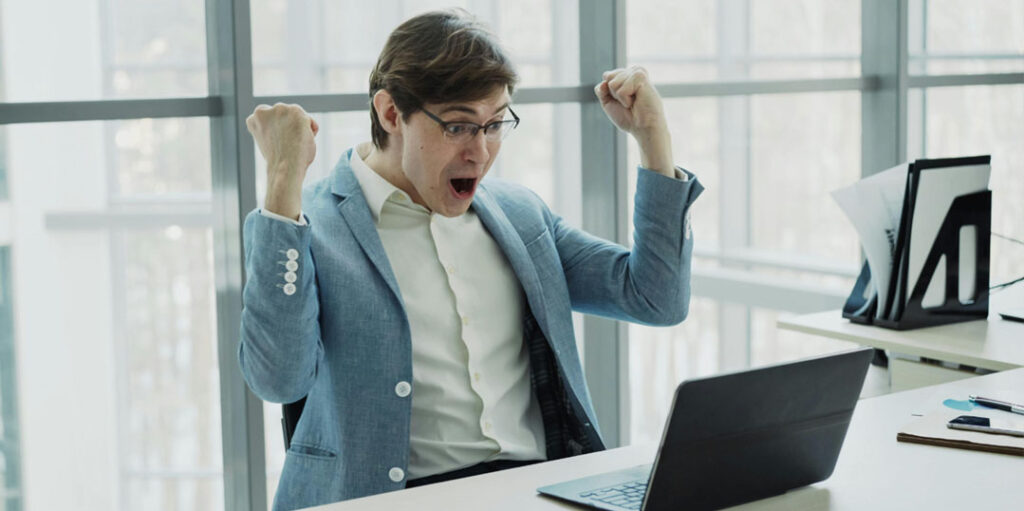 Homme heureux devant son ordinateur après une formation coaching à distance réussie