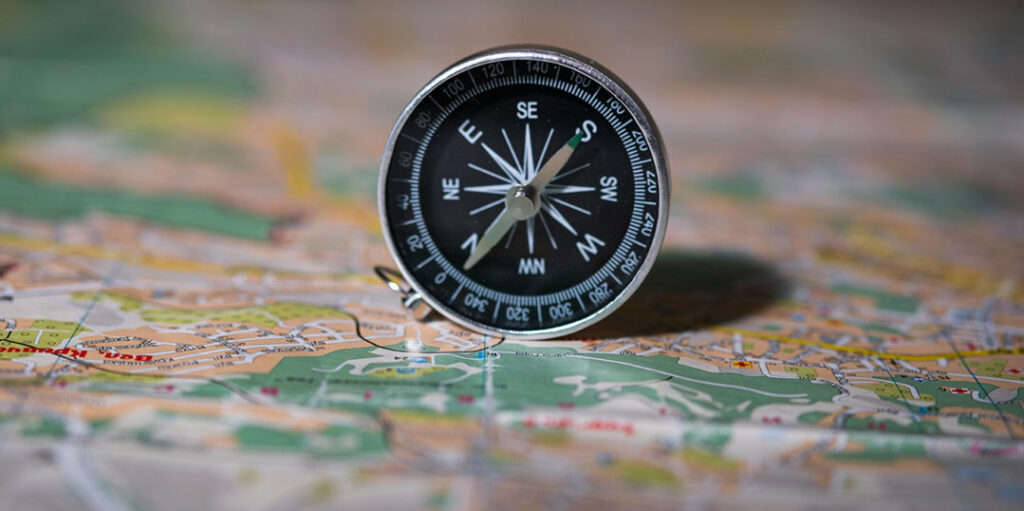 Boussole sur une carte, métaphore pour devenir coach et choisir sa direction professionnelle