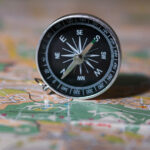 Boussole sur une carte, métaphore pour devenir coach et choisir sa direction professionnelle