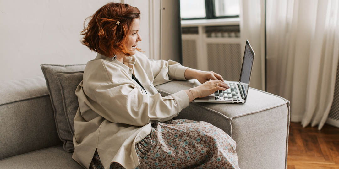 Se former à distance au coaching pour devenir coach pro c'est possible et cela commence maintenant ! Femme assise sur un canapé consultant sa formation coaching en ligne